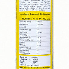 A close-up of a cylindrical can of Saravan Groundnut Oil, showing the yellow label with black text detailing ingredients, nutritional facts, and batch information.